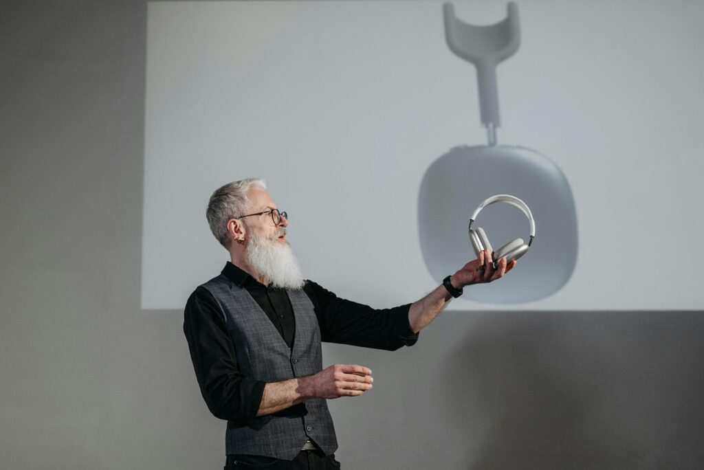 Mature man presenting wireless headphones in a business setting.